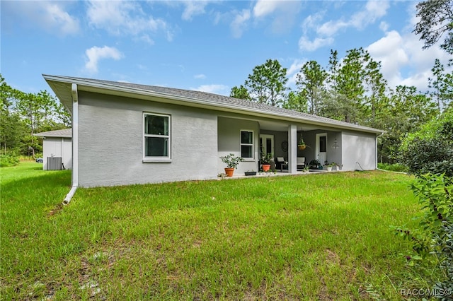 rear view of house featuring a patio, central AC, and a lawn