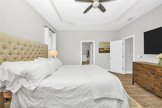 bedroom featuring a tray ceiling, ceiling fan, and hardwood / wood-style floors