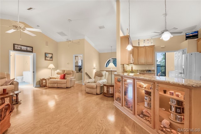 kitchen with light brown cabinets, high vaulted ceiling, hanging light fixtures, light wood-type flooring, and white fridge