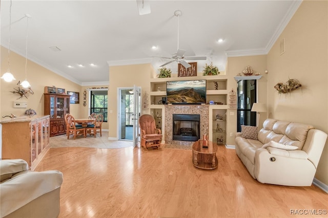 living room with ceiling fan, ornamental molding, a tile fireplace, and built in shelves