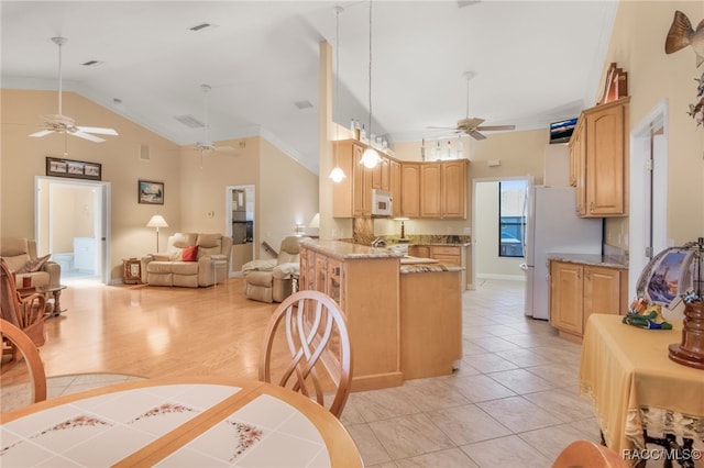 kitchen with white appliances, light brown cabinetry, decorative light fixtures, light stone counters, and kitchen peninsula