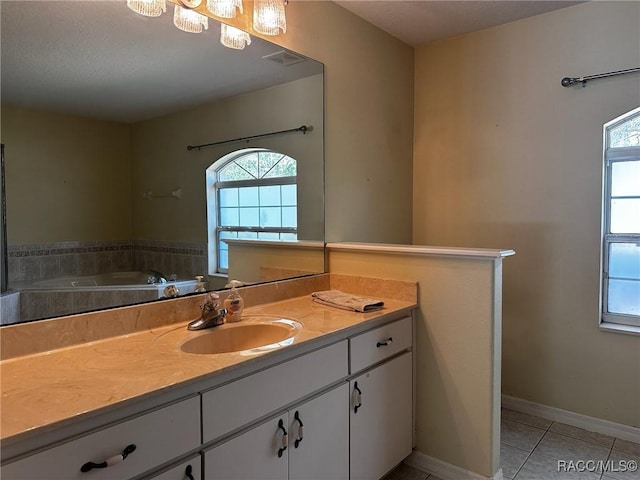 bathroom with tile patterned floors, visible vents, vanity, baseboards, and a bathtub