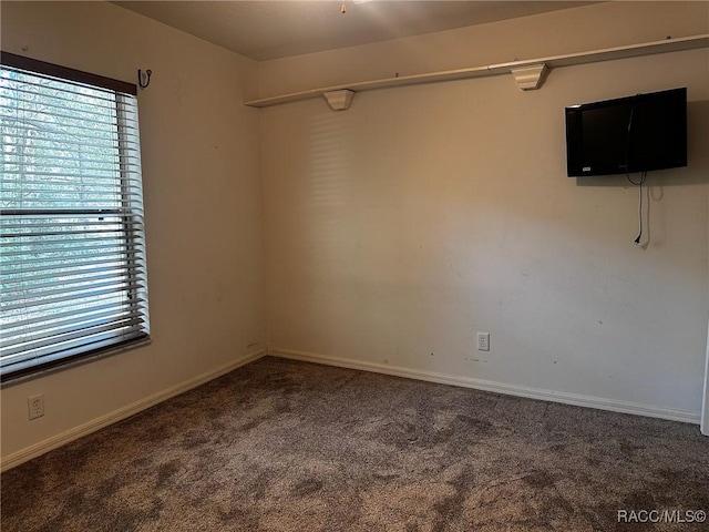 carpeted spare room featuring baseboards