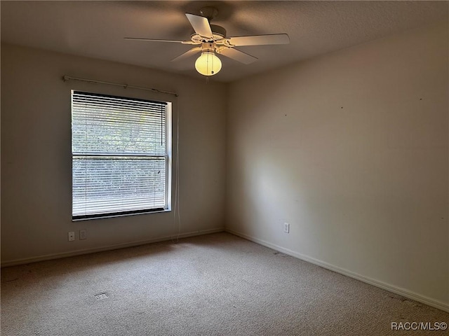 unfurnished room featuring baseboards, light colored carpet, and ceiling fan
