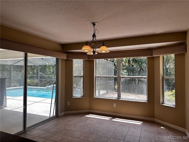 unfurnished dining area featuring baseboards, a notable chandelier, tile patterned flooring, and a textured ceiling
