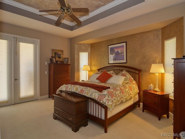 bedroom featuring ceiling fan, a tray ceiling, crown molding, and carpet flooring