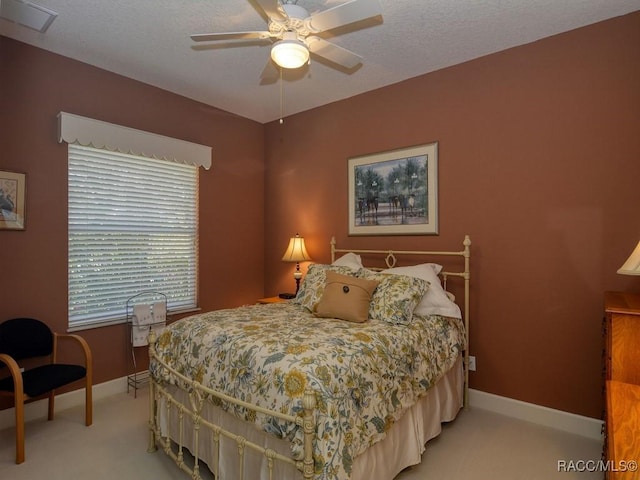 bedroom with ceiling fan, light colored carpet, and a textured ceiling