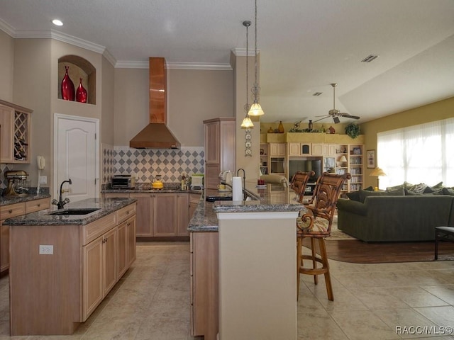 kitchen featuring vaulted ceiling, pendant lighting, kitchen peninsula, sink, and wall chimney exhaust hood