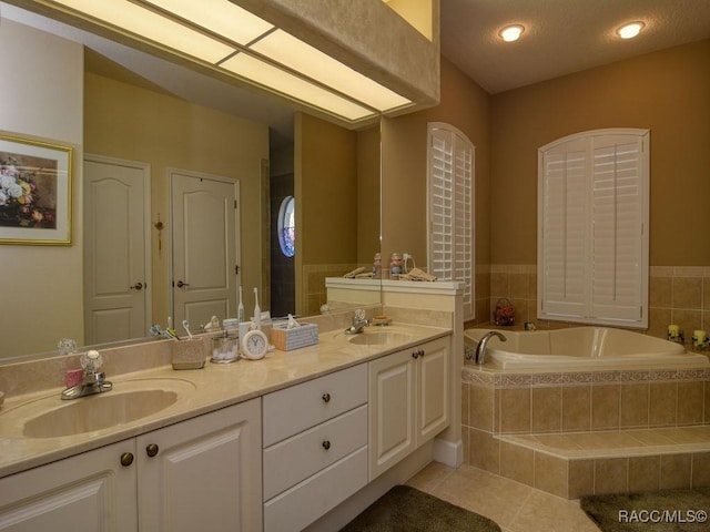 bathroom featuring a relaxing tiled tub, tile patterned floors, and vanity