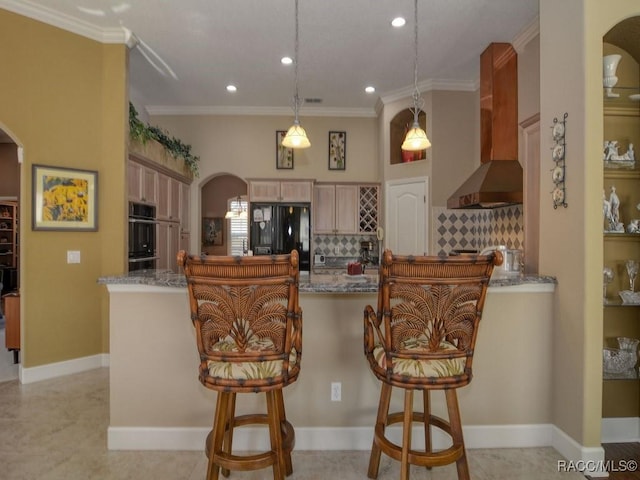 kitchen with pendant lighting, black appliances, wall chimney range hood, decorative backsplash, and light stone counters