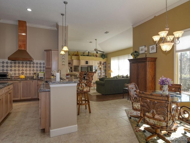 kitchen with ventilation hood, lofted ceiling, backsplash, and decorative light fixtures