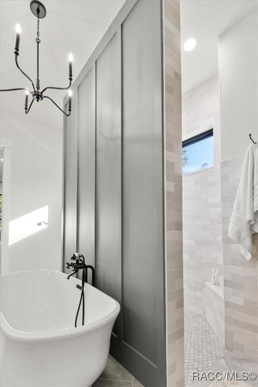 bathroom with an inviting chandelier, tile patterned flooring, and shower with separate bathtub