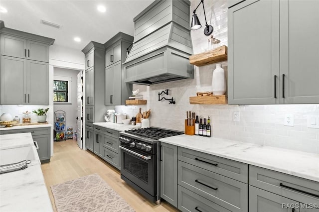 kitchen with backsplash, gas range, gray cabinets, and light hardwood / wood-style floors