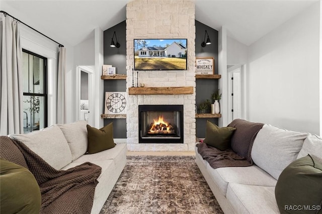 living room with built in shelves, vaulted ceiling, and a stone fireplace