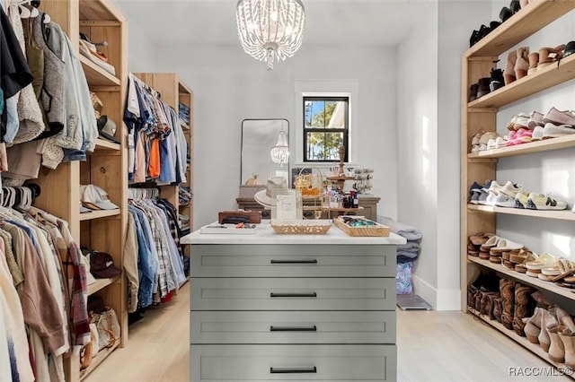 walk in closet featuring a chandelier and light wood-type flooring