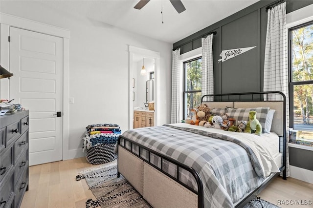 bedroom with ceiling fan, multiple windows, connected bathroom, and light wood-type flooring