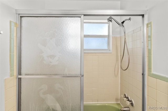 bathroom featuring shower / bath combination with glass door and tile walls