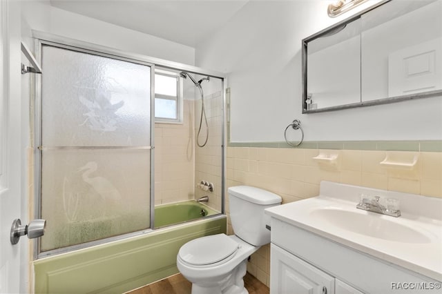 full bathroom with shower / bath combination with glass door, vanity, hardwood / wood-style flooring, and tile walls