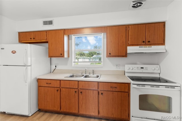 kitchen with light wood-type flooring, white appliances, and sink