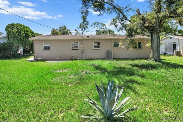 back of property with a lawn and central AC