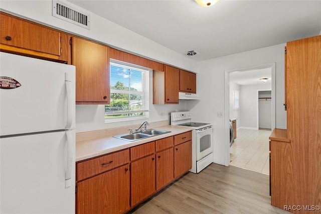 kitchen featuring light wood-type flooring, white appliances, sink, and washer / dryer