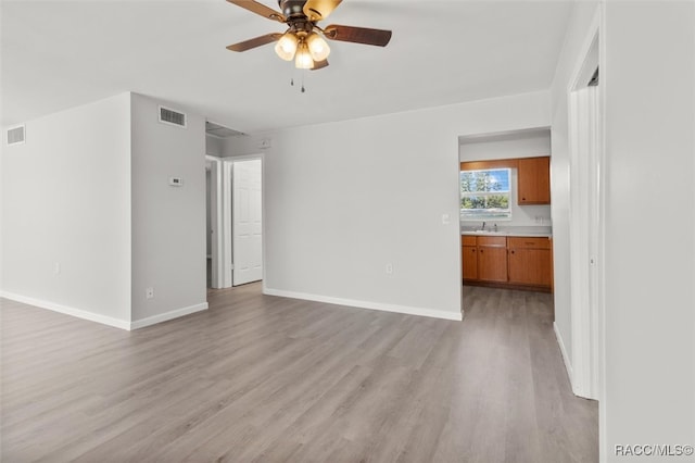 unfurnished room with light wood-type flooring, ceiling fan, and sink