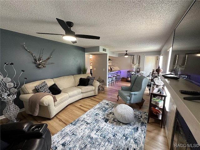 living room with hardwood / wood-style floors, a textured ceiling, and ceiling fan