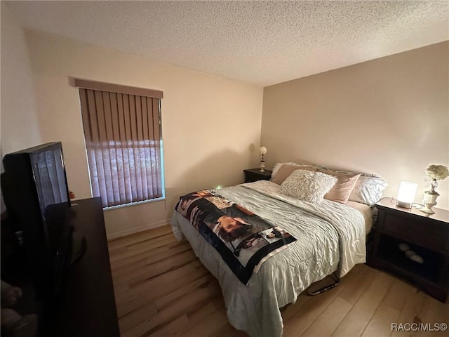 bedroom with wood-type flooring and a textured ceiling