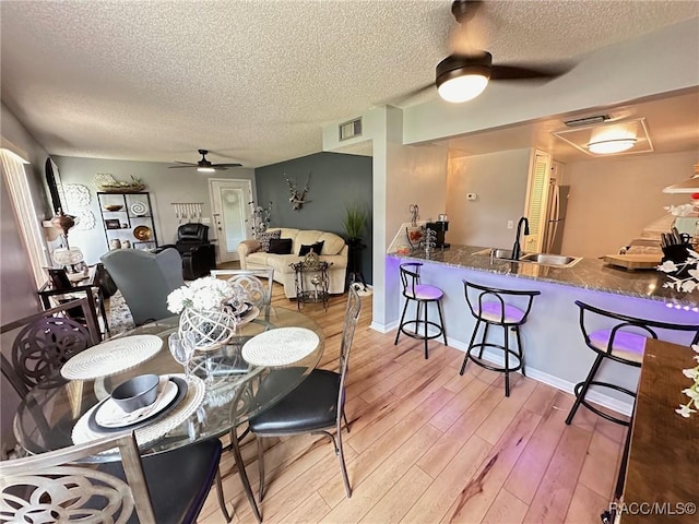 dining space featuring hardwood / wood-style flooring, ceiling fan, sink, and a textured ceiling