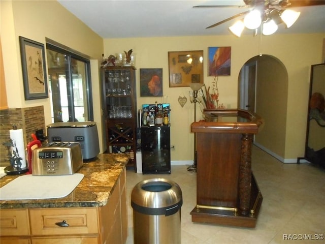 bar with ceiling fan and light brown cabinetry