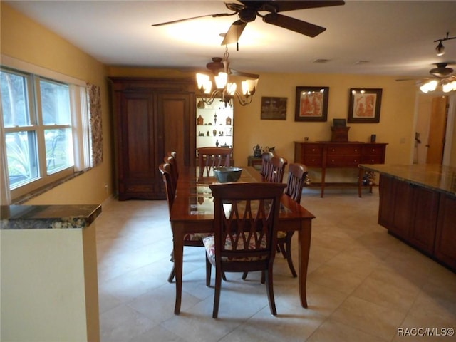 dining space with ceiling fan with notable chandelier