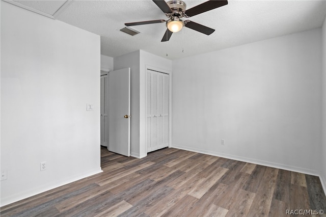 unfurnished bedroom featuring dark hardwood / wood-style floors, ceiling fan, and a textured ceiling