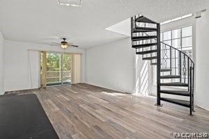 unfurnished living room with ceiling fan, a textured ceiling, and hardwood / wood-style flooring