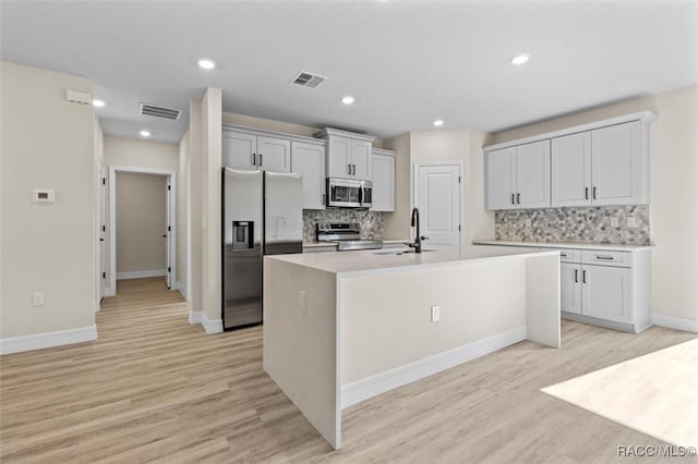 kitchen featuring visible vents, light countertops, appliances with stainless steel finishes, and a center island with sink