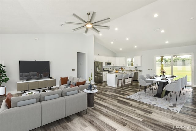 living room featuring hardwood / wood-style flooring, ceiling fan, and high vaulted ceiling