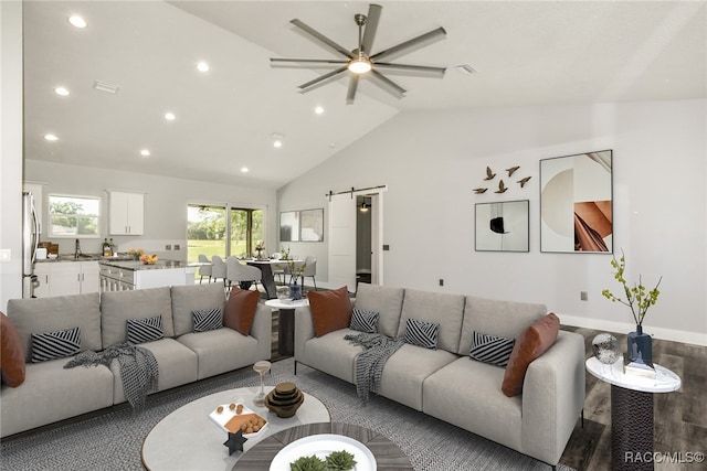 living room with a barn door, vaulted ceiling, and ceiling fan