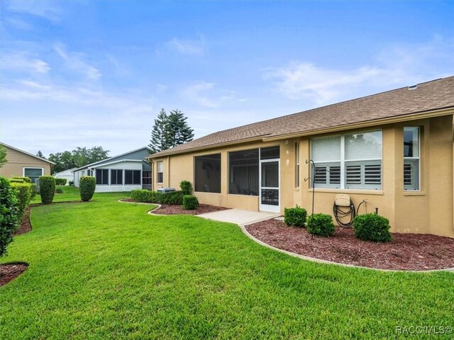 18514 Hidden Pines Way, Hudson, FL 34667 - rear view of house with stucco siding, a yard, and a sunroom