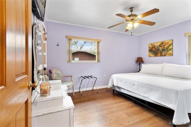 bedroom with ornamental molding, light wood-type flooring, baseboards, and a ceiling fan