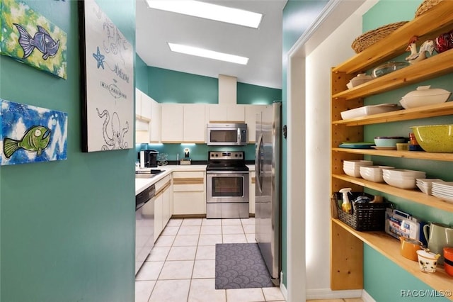 kitchen with light tile patterned flooring, stainless steel appliances, a sink, white cabinets, and light countertops