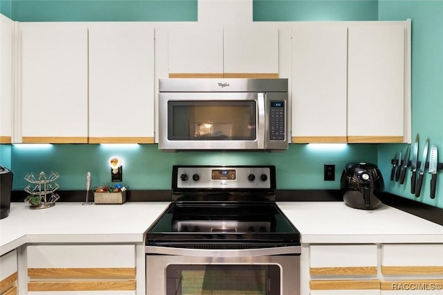 kitchen featuring white cabinetry, stainless steel appliances, and light countertops