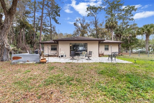 rear view of property featuring a patio area, a yard, fence, and stucco siding