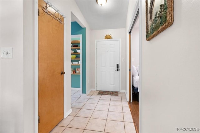 corridor featuring baseboards and light tile patterned flooring