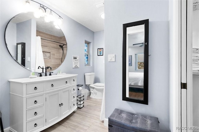 bathroom with ceiling fan, curtained shower, connected bathroom, toilet, and vanity