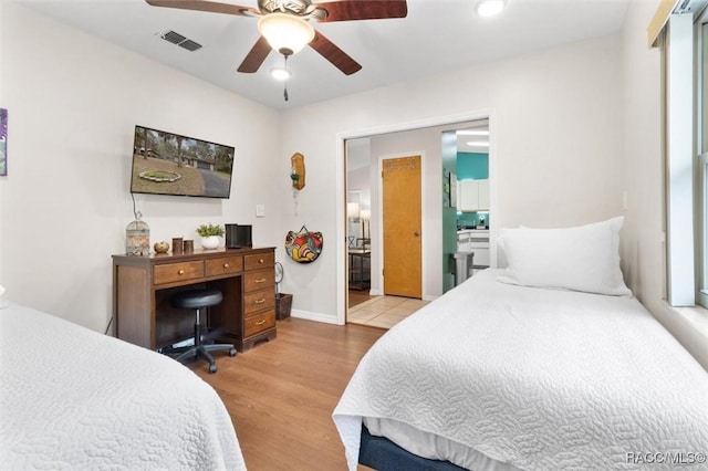 bedroom with baseboards, visible vents, a ceiling fan, connected bathroom, and wood finished floors