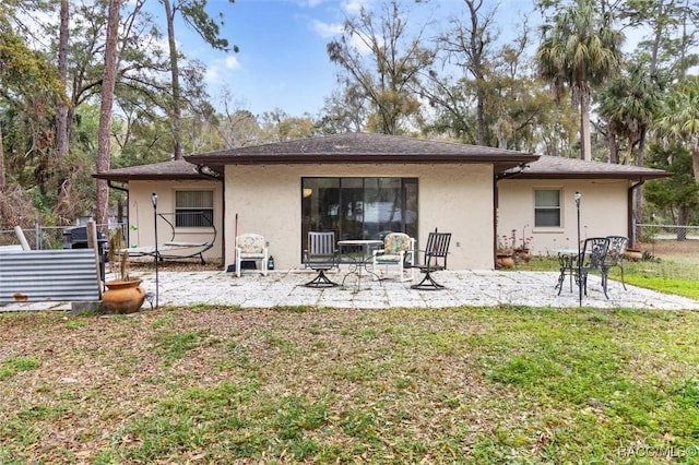 back of property with stucco siding, a yard, fence, and a patio