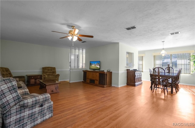 living room with ceiling fan, light hardwood / wood-style floors, and a textured ceiling