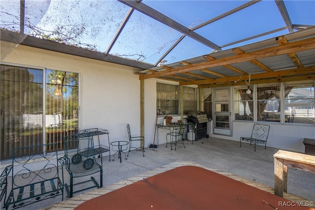 view of patio featuring glass enclosure and area for grilling