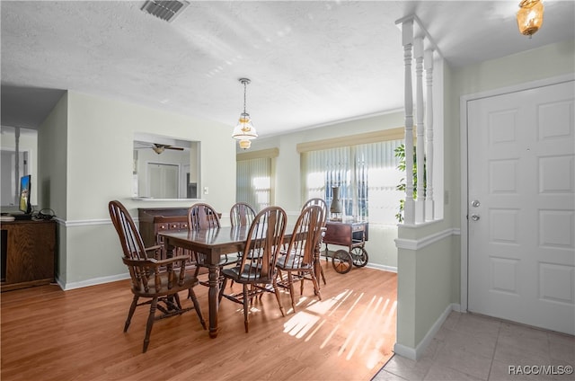 dining space featuring ceiling fan, light hardwood / wood-style flooring, and a textured ceiling