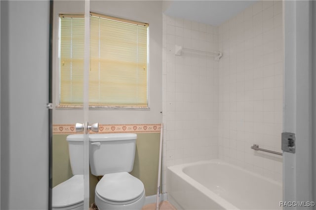 bathroom featuring toilet and tiled shower / bath