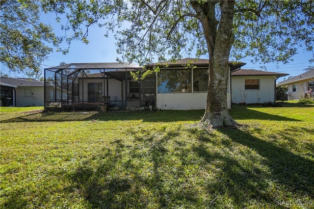 rear view of property with a lanai and a lawn